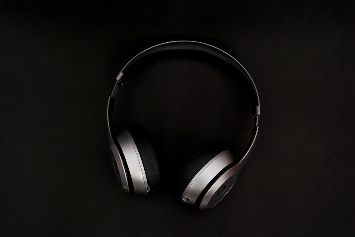 Fones de ouvido prateados sobre uma superfície preta.